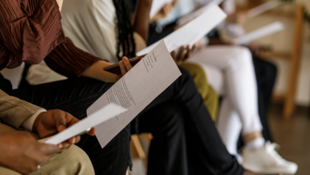 Row of people sitting down holding a piece of paper